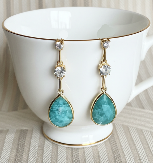 A pair of 925 sterling silver gold-tone earrings featuring amazonite gemstones and cubic zirconia, displayed against a patterned background.