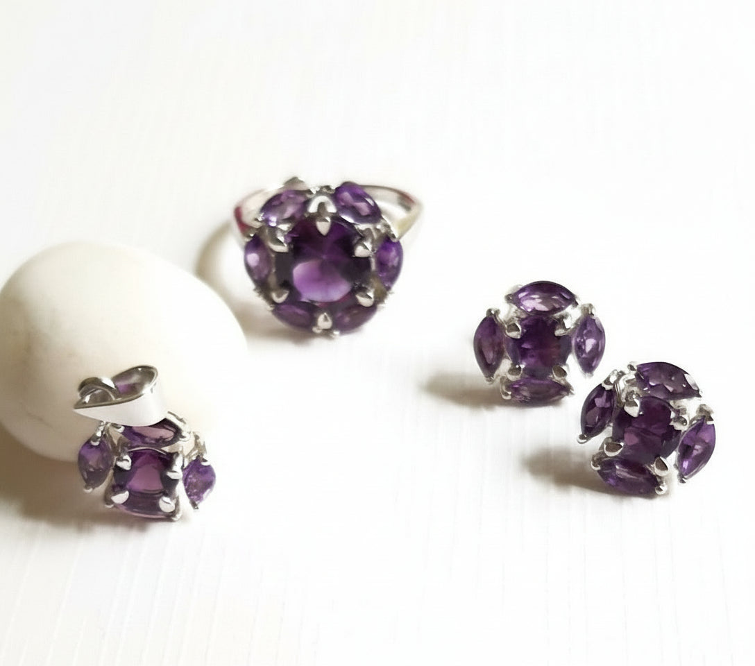 A set of 925 sterling silver jewellery jewelry featuring amethyst stones, including round earrings, a pendant, and an adjustable finger ring, displayed on a white surface.