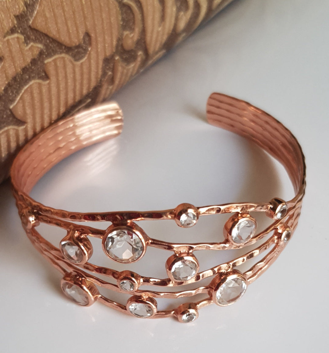 Office wear jewellery Rose gold bracelet with embedded stones on a textured surface