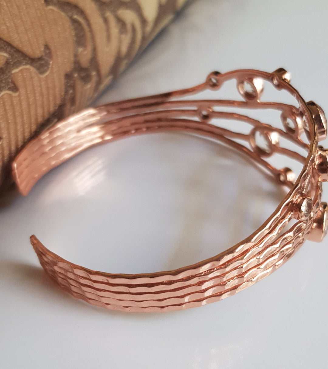 Office wear Rose gold bracelet on a white surface with a textured background