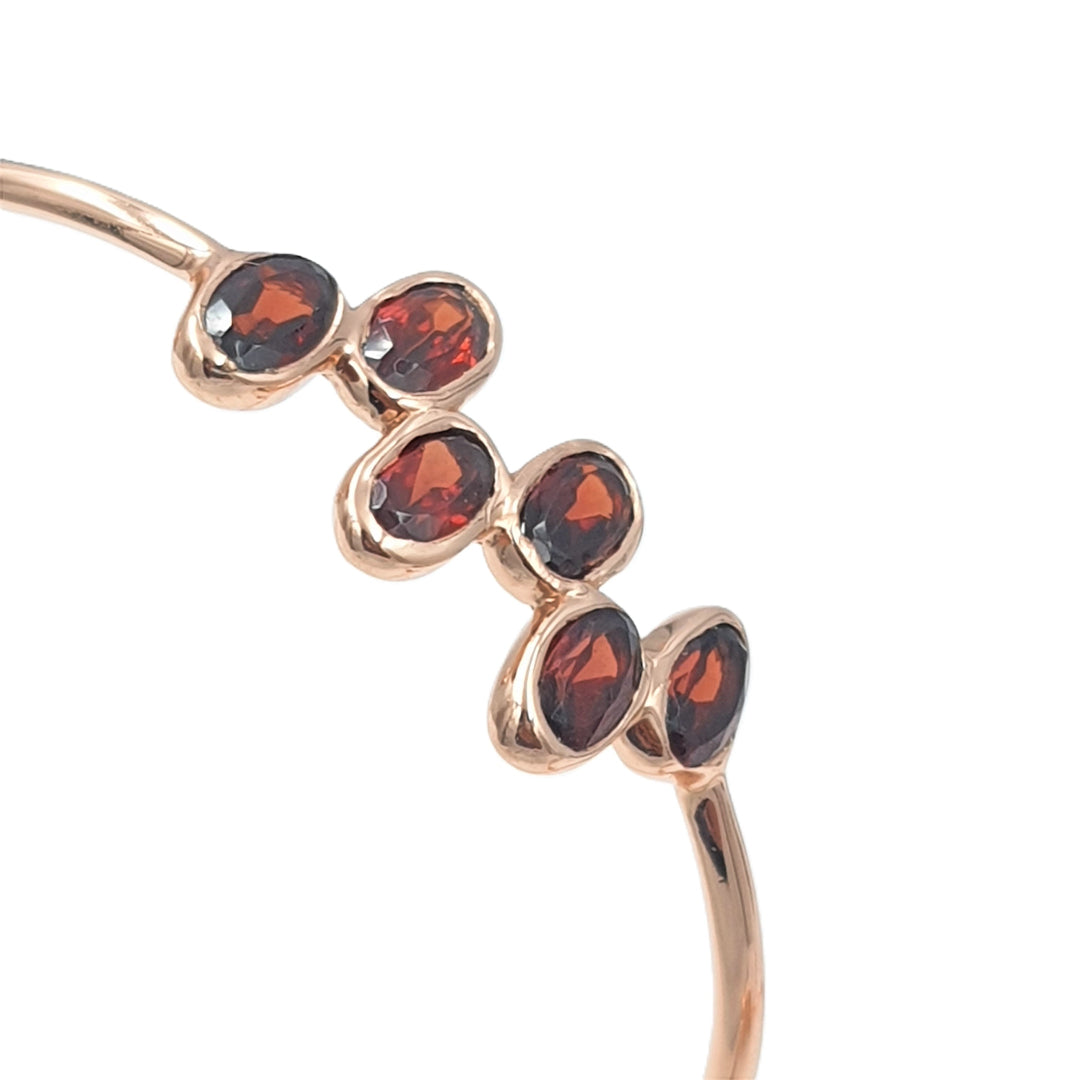 Close-up of rose-gold plated hoop earrings with garnet gemstones, highlighting their rich red sparkle and fine detailing.