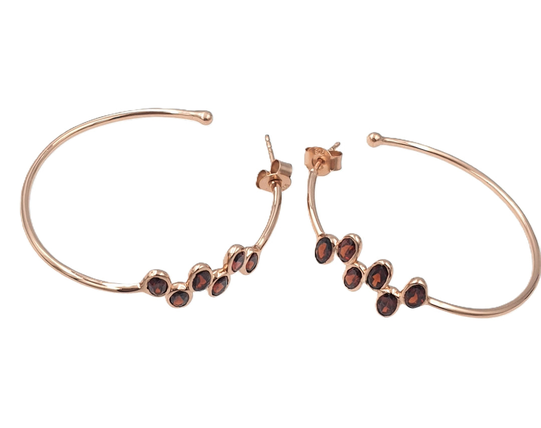 Side view of garnet hoop earrings in rose-gold plated 92.5 sterling silver, showing their slim, elegant silhouette.