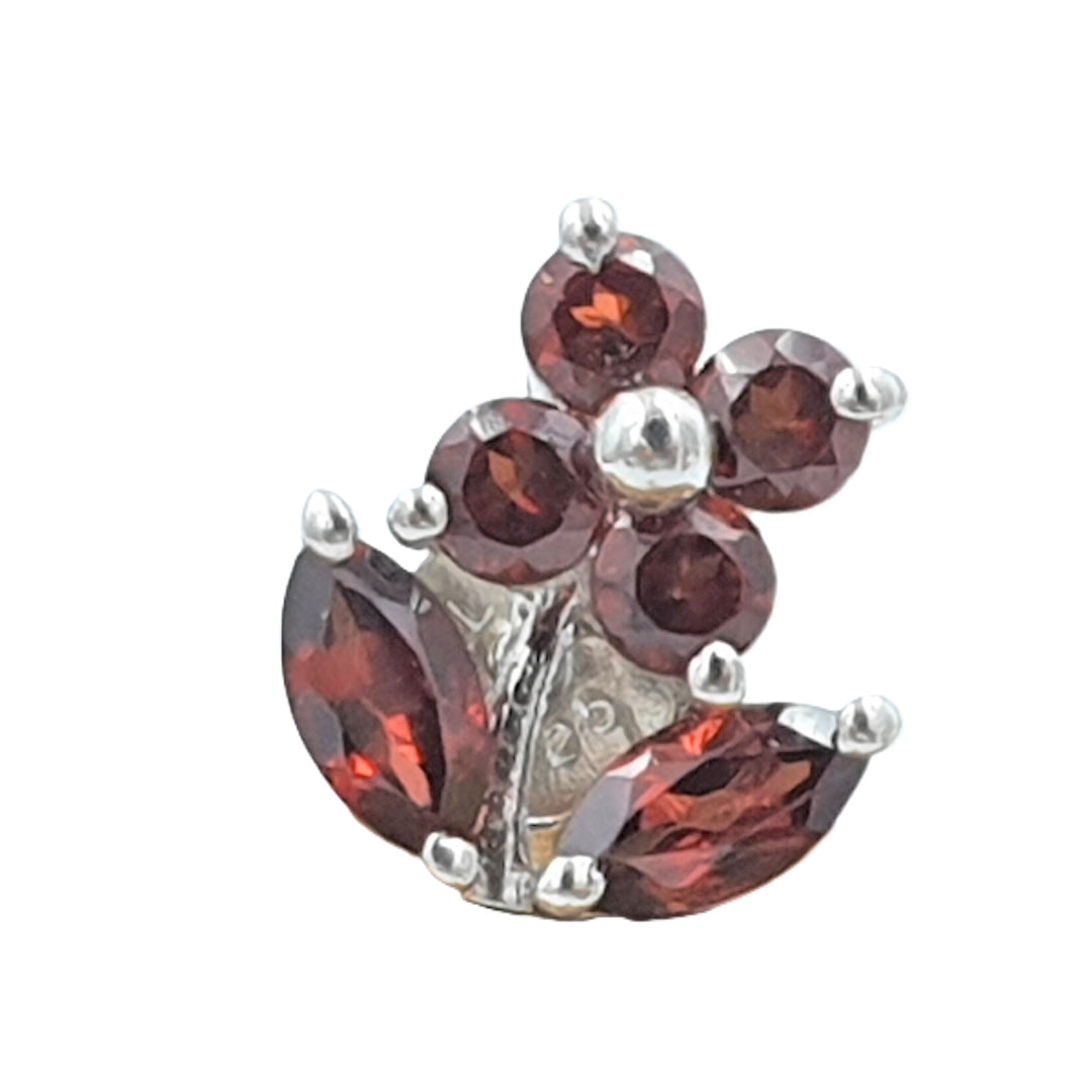 Close-up of rhodium-finished 92.5 sterling silver earrings with deep red garnet gemstones, highlighting the detailed floral styling.