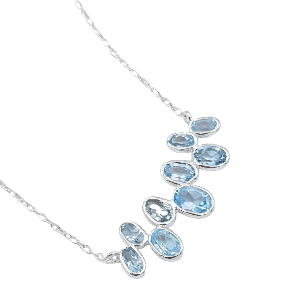 Tight close-up of blue topaz necklace links in sterling silver, showcasing the smooth finish and bright blue sparkle.