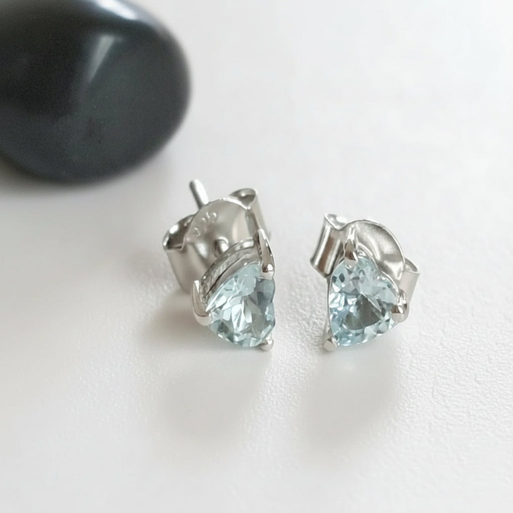 A pair of sterling silver earrings with round Aquamarine stones, displayed against a fabric background.