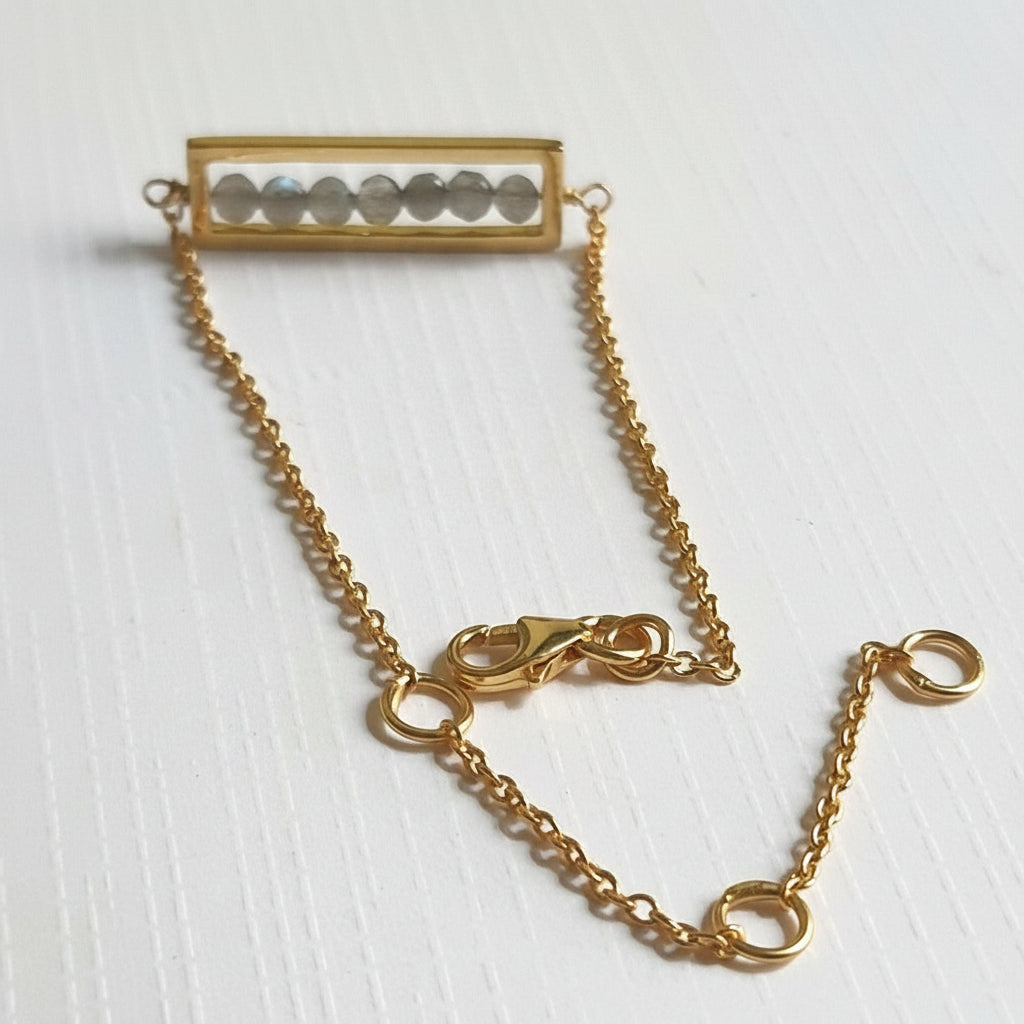 A 925 sterling silver gold plated bracelet featuring a bar-shaped motif with multiple small labradorite stones set within.