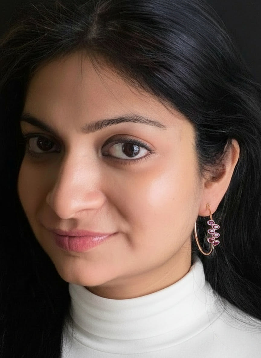 Garnet hoop earrings in rose-gold plated 92.5 sterling silver worn by a woman, showcasing their elegant and romantic look when styled.