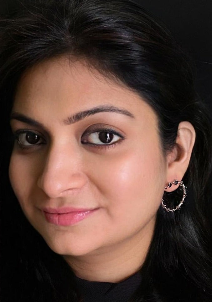 Black onyx front-facing hoop earrings in rhodium-plated 92.5 sterling silver worn by a woman, showing their modern, elegant look when styled.