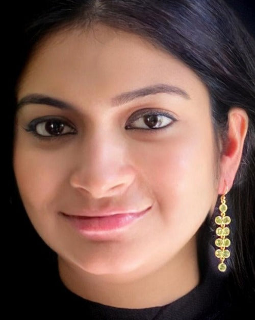 Peridot gemstone earrings in 925 sterling silver with yellow-gold plating worn by a woman, showing how the wisteria-inspired design looks when styled.